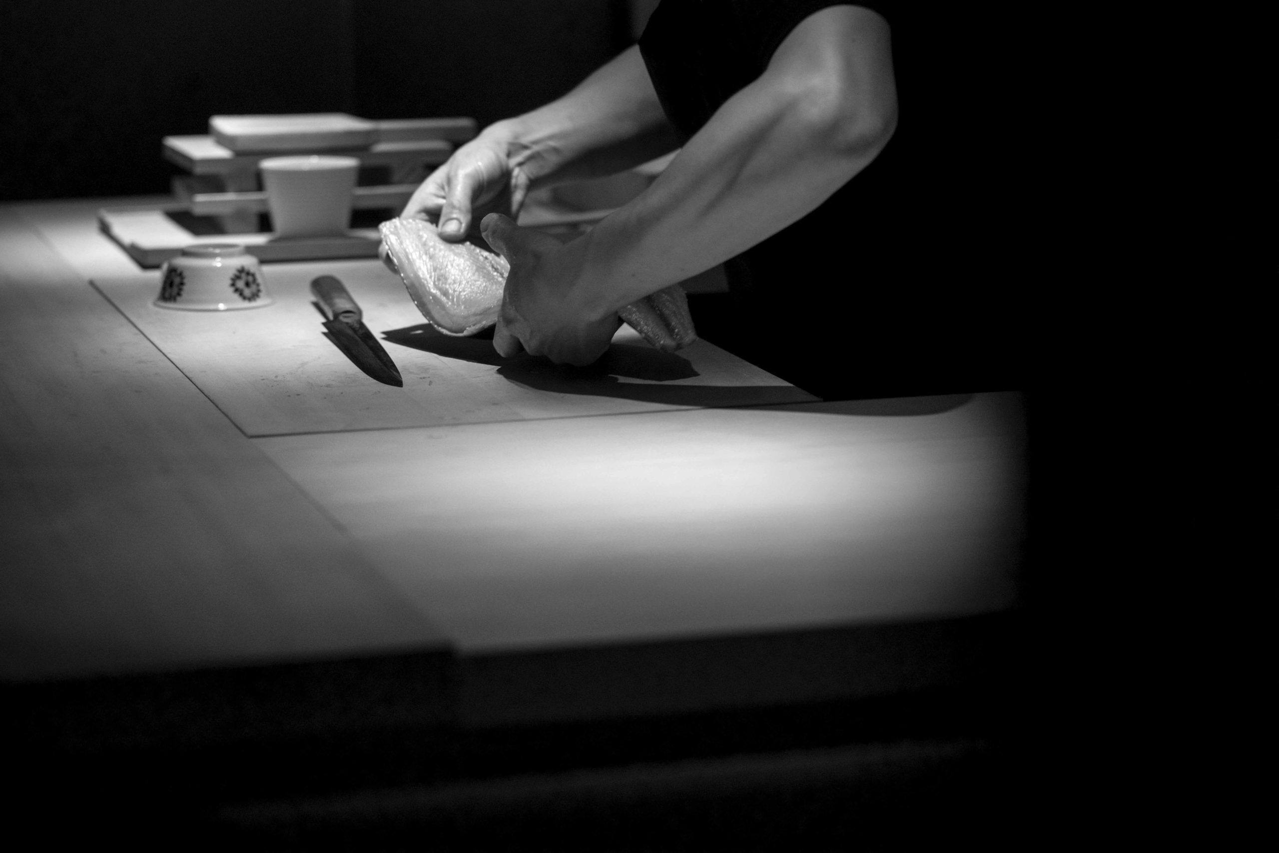 photo en noir et blanc par Laurent Dupont d'un cuisinier qui découpe un saumon